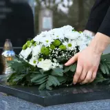 Dłoń kładzie wieniec na nagrobku. Pytanie, ile trwa żałoba w kościele katolickim, jest trudne.
