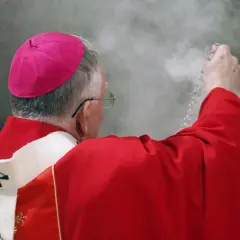 Biskup w czerwonej szacie i różowym birecie okadza powietrze. Czy to wpływa na to, ile zarabia ksiądz?