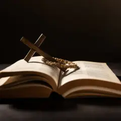 Otwarta księga, krzyż i wieniec cierniowy – symbole chrześcijaństwa w mrocznym świetle.