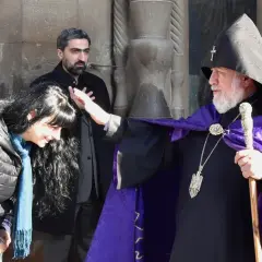 Błogosławieństwo kobiety przez duchownego w tradycyjnym ornamencie. Scena ukazuje głębokie korzenie armenia religia.