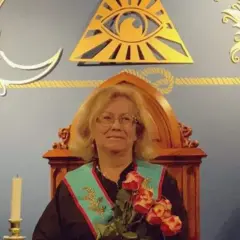 Kobieta w szatach siedzi na ozdobnym tronie, otoczona symbolami wolnomularzy: Okiem Opatrzności, słońcem i księżycem.
