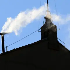 Biały dym z komina na tle błękitnego nieba, jakby papież ogłaszał wybór.