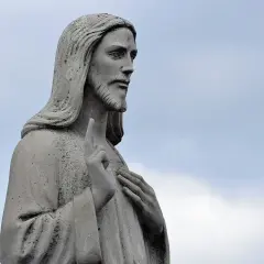 Kamienna rzeźba Jezusa z podniesionym palcem, jakby w geście błogosławieństwa lub modlitwy za rodziców.