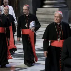 Kardynałowie w czarnych szatach z czerwonymi pasami idą w procesji. To ważny moment, zbliża się wybór papieża.