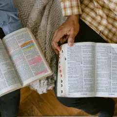 Dwie osoby studiują Ewangelia św Jana, zaznaczone fragmenty tekstu.