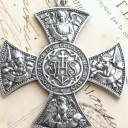 Srebrny krzyż z symbolami ewangelistów: lew (św. Marek), wół (św. Łukasz), anioł (św. Mateusz) i orzeł (św. Jan). Centralnie umieszczony monogram IHS.