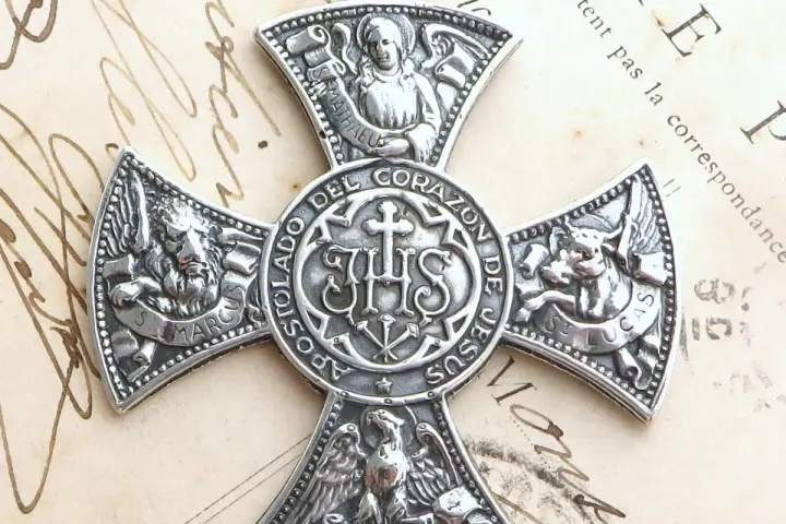 Srebrny krzyż z symbolami ewangelistów: lew (św. Marek), wół (św. Łukasz), anioł (św. Mateusz) i orzeł (św. Jan). Centralnie umieszczony monogram IHS.