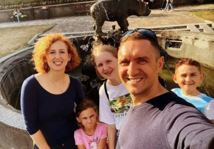 Rodzina pozuje do zdjęcia przy fontannie z rzeźbą niedźwiedzia.