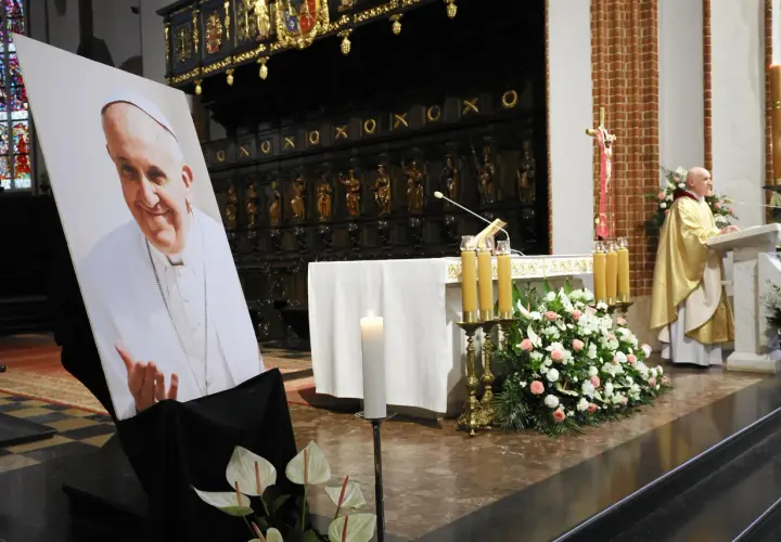 Papieski pontyfikat upamiętniony portretem i kwiatami w kościele.