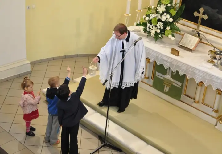 Dzieci na nabożeństwie w kościele luterańskim. Ksiądz z kadzielnicą błogosławi zgromadzonych.