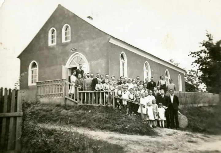 Grupa ludzi, w tym dzieci, pozuje przed budynkiem kościoła. Prawdopodobnie to zgromadzenie mormonów z lat 30. XX wieku.