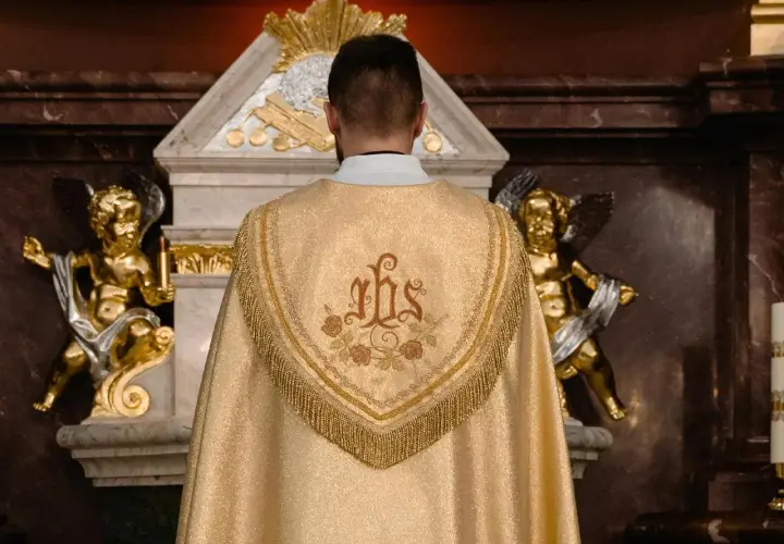 Kapłan w złotej kapie z symbolem IHS. Złote aniołki po bokach ołtarza. Zastanawiasz się, ile trwa msza?
