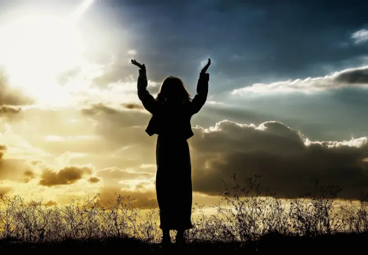 Sylwetka osoby z rękami w górze, na tle dramatycznego nieba, jak w psalm 47.