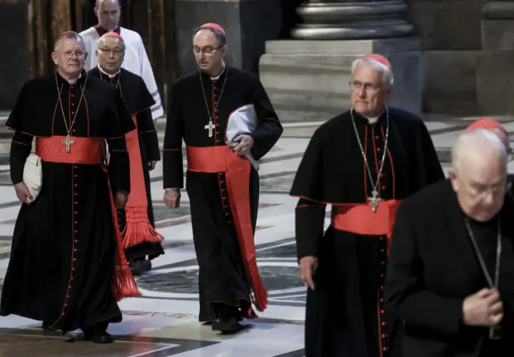 Kardynałowie w czarnych szatach z czerwonymi pasami idą w procesji. To ważny moment, zbliża się wybór papieża.