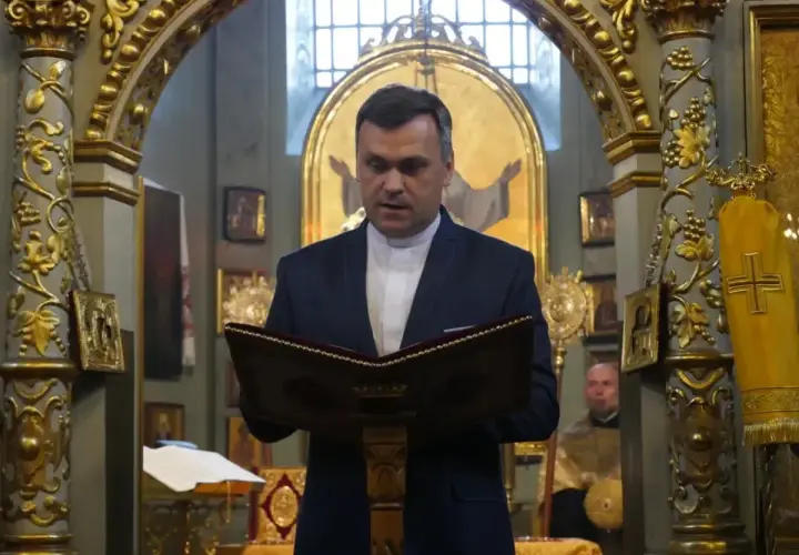 Duchowny w kościele polskokatolickim czyta z księgi. Różnice między kościołem polskokatolickim a rzymskokatolickim są widoczne w wystroju.