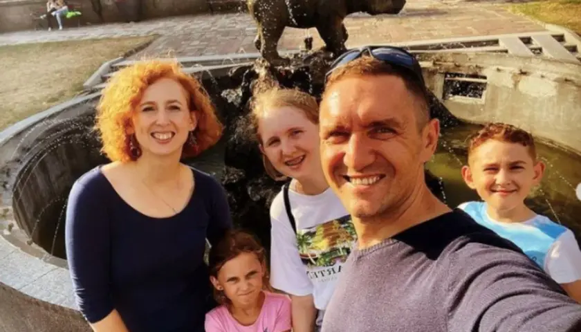 Rodzina pozuje do zdjęcia przy fontannie z rzeźbą niedźwiedzia.