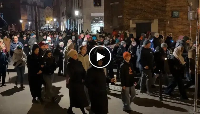 Tłum ludzi idzie ulicą nocą, trzymając świece. To wygląda jak Droga Krzyżowa.
