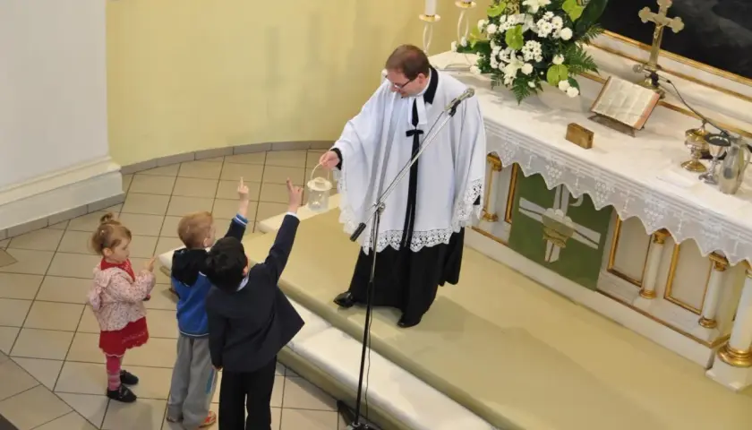 Dzieci na nabożeństwie w kościele luterańskim. Ksiądz z kadzielnicą błogosławi zgromadzonych.