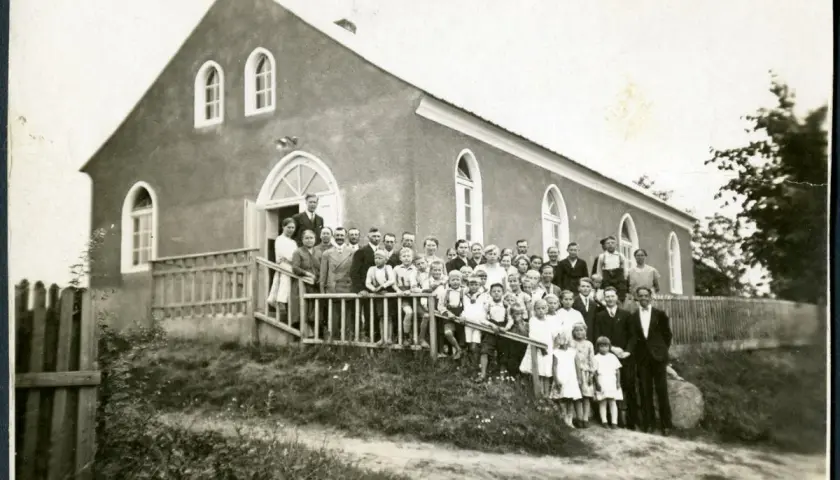 Grupa ludzi, w tym dzieci, pozuje przed budynkiem kościoła. Prawdopodobnie to zgromadzenie mormonów z lat 30. XX wieku.