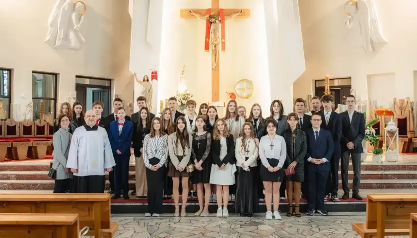 Młodzież w kościele, gotowa do bierzmowania w jakim wieku. Uroczystość z księdzem i rodzinami.