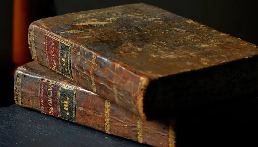 Dwa stare, skórzane tomy, jeden na drugim. Na grzbietach widoczne złote zdobienia i etykiety, jedna z nich zawiera fragment "psalm 15".