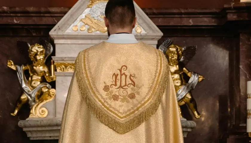 Kapłan w złotej kapie z symbolem IHS. Złote aniołki po bokach ołtarza. Zastanawiasz się, ile trwa msza?