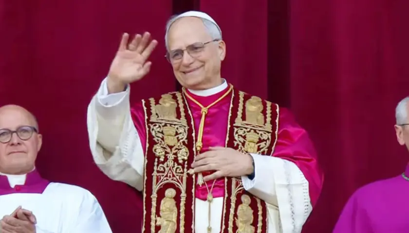 Nowy papież w bogato zdobionej szacie pozdrawia wiernych.