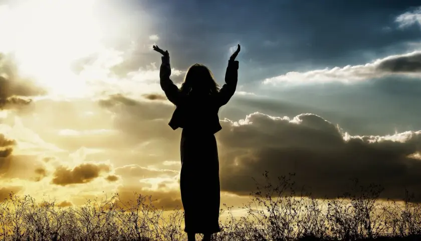 Sylwetka osoby z rękami w górze, na tle dramatycznego nieba, jak w psalm 47.