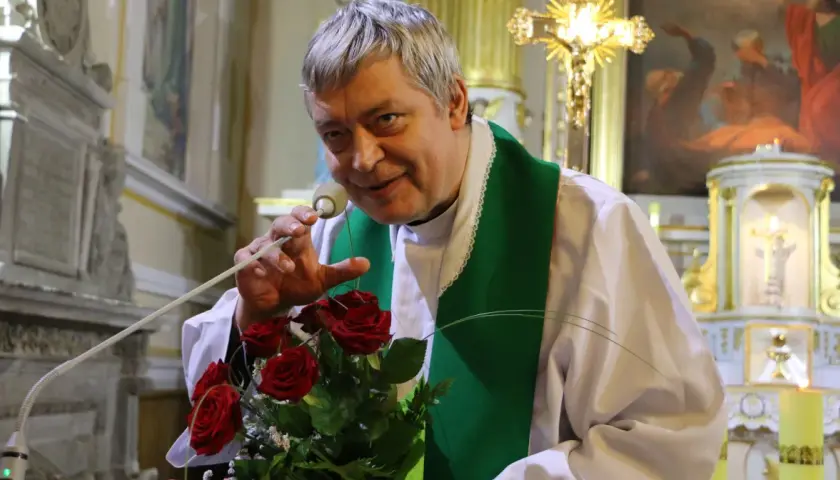 Ksiądz Piotr z bukietem róż, jak Piotr i Paweł, przemawia do wiernych w kościele.