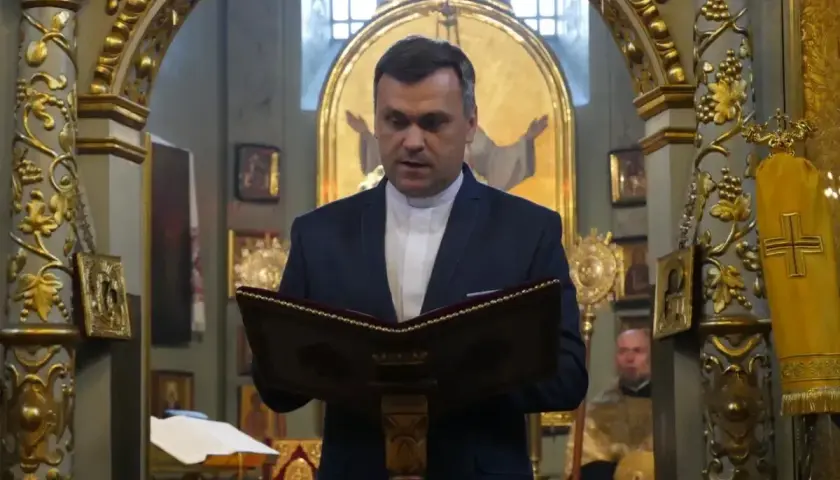 Duchowny w kościele polskokatolickim czyta z księgi. Różnice między kościołem polskokatolickim a rzymskokatolickim są widoczne w wystroju.