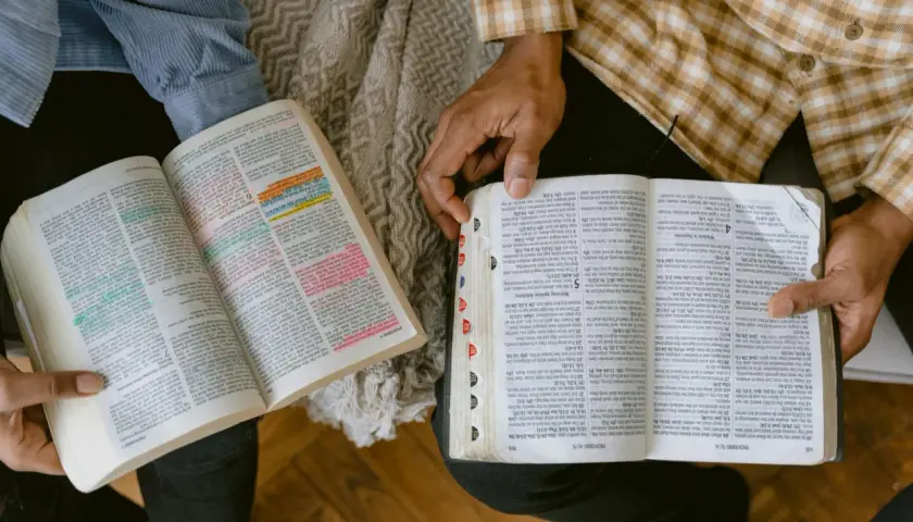 Dwie osoby studiują Ewangelia św Jana, zaznaczone fragmenty tekstu.
