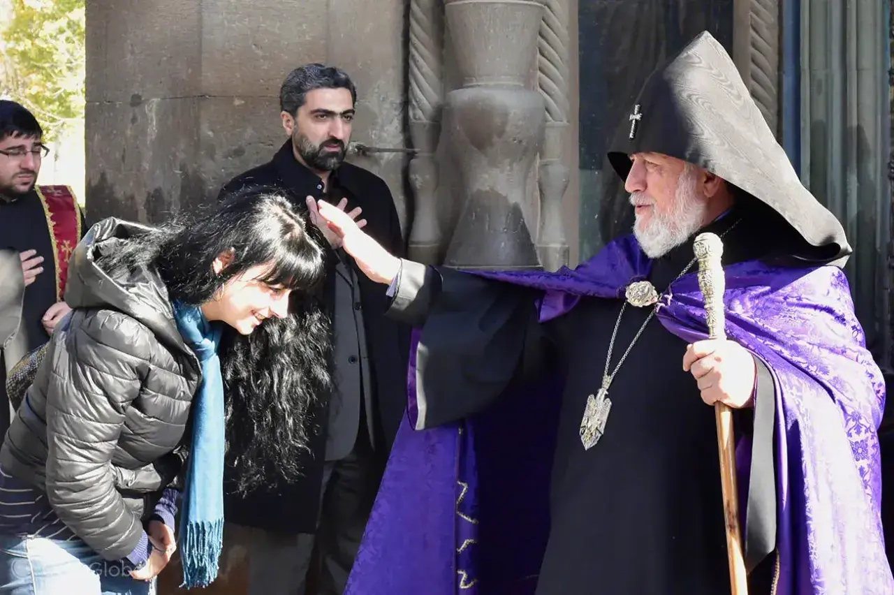 Błogosławieństwo kobiety przez duchownego w tradycyjnym ornamencie. Scena ukazuje głębokie korzenie armenia religia.