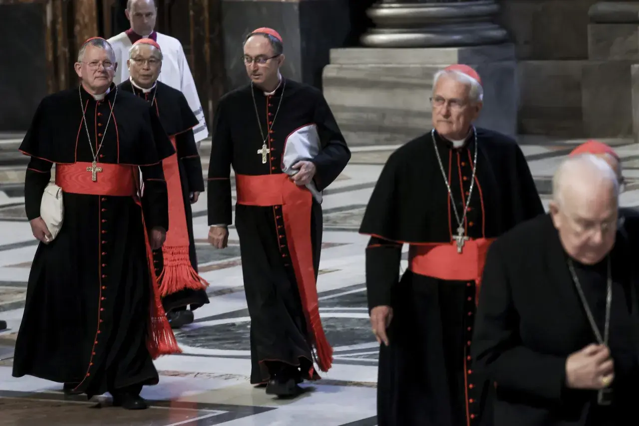 Kardynałowie w czarnych szatach z czerwonymi pasami idą w procesji. To ważny moment, zbliża się wybór papieża.