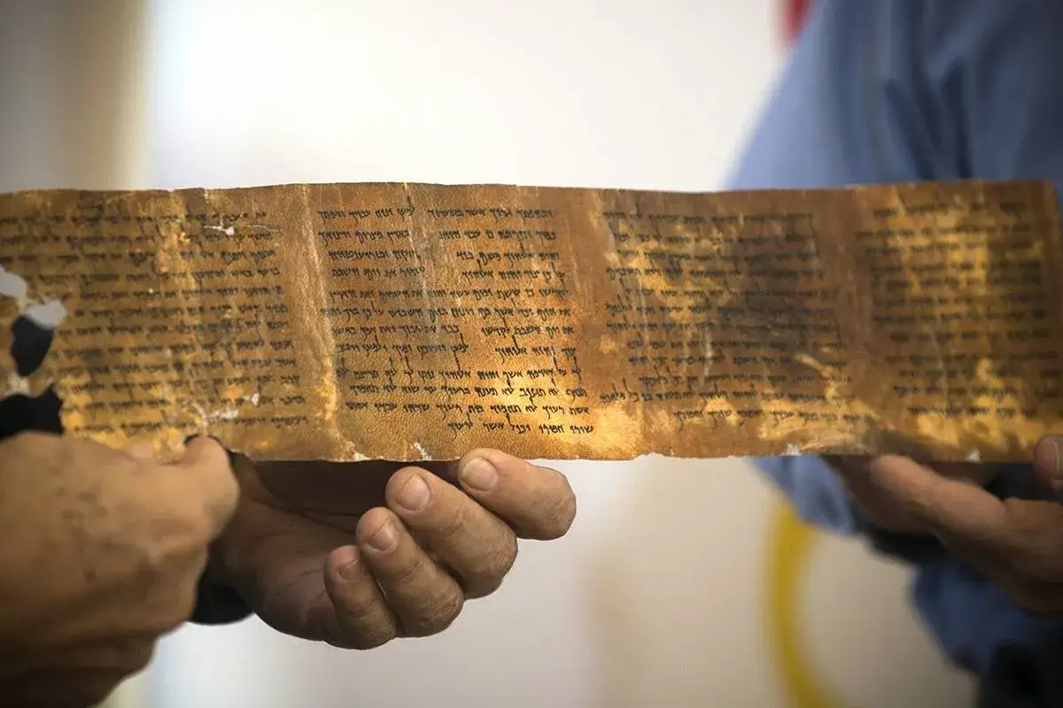 Starożytny zwój z tekstem, być może fragment psalm 135, trzymany w dłoniach.