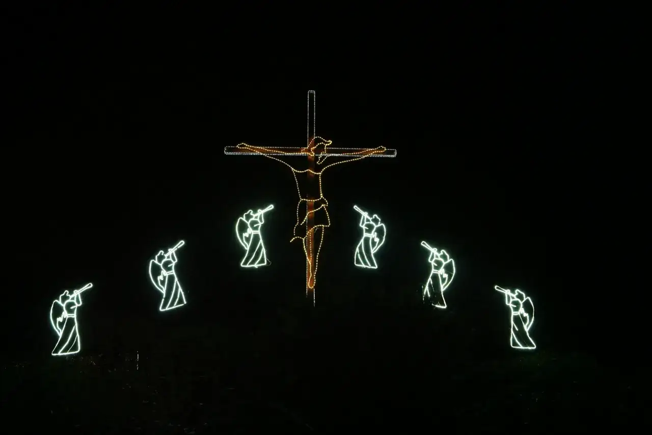 Świecący krzyż z postacią Jezusa i aniołami grającymi na trąbach, symbolizujący cnoty kardynalne.
