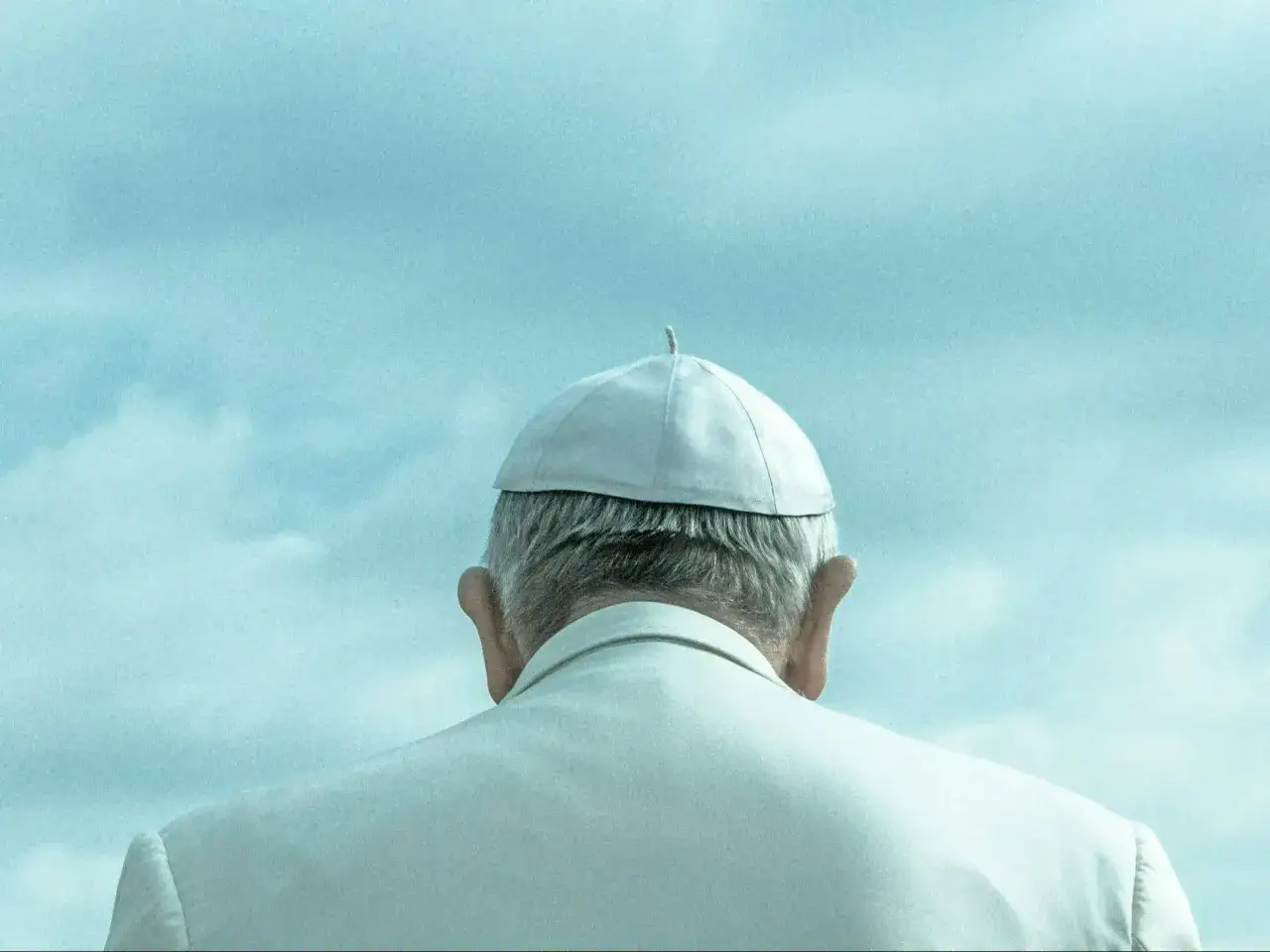 Papież w białej sutannie i piusce, odwrócony plecami, patrzy w niebo. Symboliczny obraz wyboru papieża.